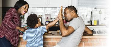 parents and kid in kitchen giving a high five